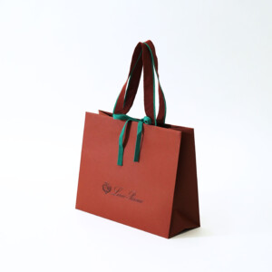 クラシカルな色合いの本体にエンボス加工と箔押しが施された、深い歴史のある服地のトップメーカーの高級感溢れるオリジナル紙袋