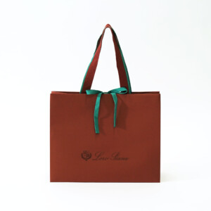 クラシカルな色合いの本体にエンボス加工と箔押しが施された、深い歴史のある服地のトップメーカーの高級感溢れるオリジナル紙袋