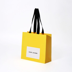 鮮やかなデイジーイエローにブラックの箔押しのロゴが映える、世界的有名ファッションブランドの「遊び心」が感じられる素敵なオリジナル紙袋