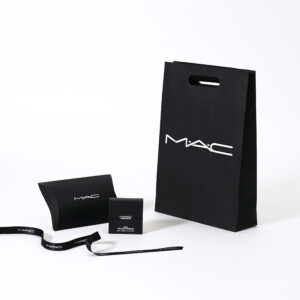 モノトーンの紙袋本体に小判抜きが施された、有名コスメブランドの洗練された印象のオリジナル紙袋