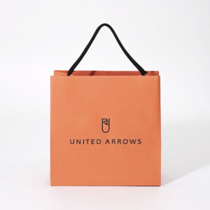 落ち着いたオレンジ色にブラックの箔押しのブランドロゴが映える、大人に向けたドレス軸のライフスタイルを提案するセレクトショップのオリジナル紙袋