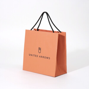 落ち着いたオレンジ色にブラックの箔押しのブランドロゴが映える、大人に向けたドレス軸のライフスタイルを提案するセレクトショップのオリジナル紙袋