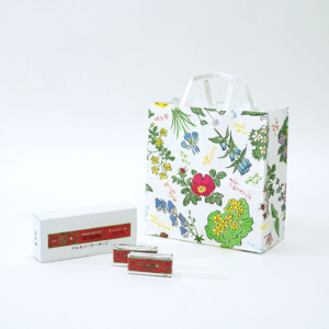 白色のクラフト紙にフルカラーで華麗な花柄をあしらった、北海道の有名和菓子メーカーの美しいオリジナル紙袋とマルセイバターサンドの復刻デザインが施されたレトロなオリジナルボックス