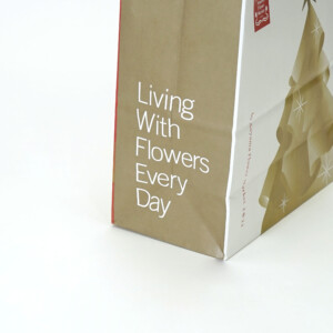 ゴールドのクリスマスツリーと星がデザインされた、クラフト紙に全面フルカラー印刷された、フラワーショップのホリデー限定オリジナル紙袋