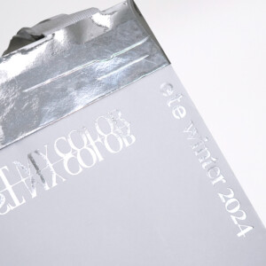 シルバー箔で「JUST MY COLOR」と「ete winter 2024」が印字された紙袋のフロント部分