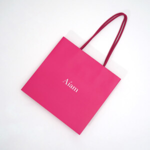 ビビッドピンクの紙袋にブランドロゴが光る