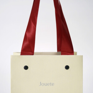 コットンホワイトに赤リボンが映える、エンボス加工が美しいジュエリーブランドの特別感あふれるオリジナル紙袋