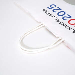 晒クラフト素材が持つ温かい風合いに、大阪・関西万博のシンボルキャラクター「ミャクミャク」がデザインされた、サステナブルなオリジナル紙袋