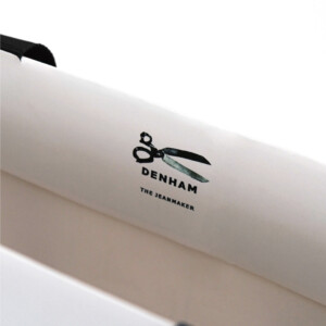 ハサミのロゴと公式URLを口折り部分にデザイン。情報伝達も兼ね備えたプレミアムデニムブランドのオリジナル紙袋